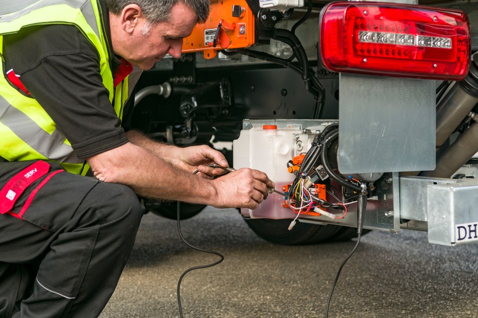 Engineer inspecting tail lift electrical components and wiring